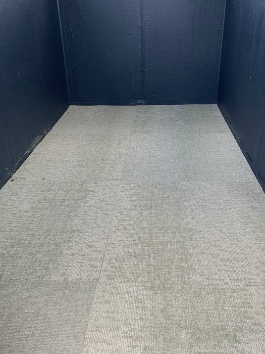 Carpeted floor inside a deer blind, meeting flat black interior walls